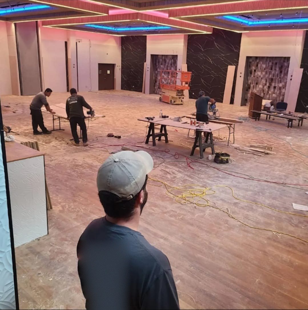 Crew working in a large commercial ballroom during renovation, with temporary power cords on the floor