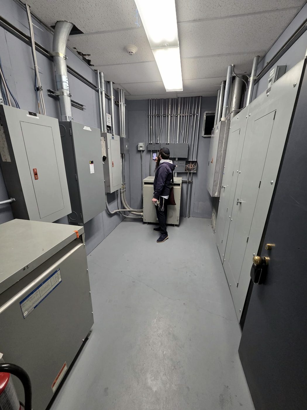 Electrical contractor working in a commercial electrical room with panels
